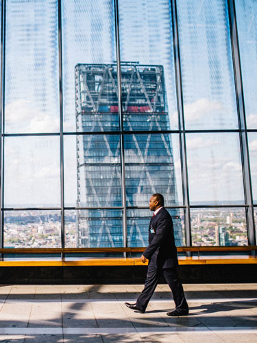 photo of a man walking with a skyscraper in the background